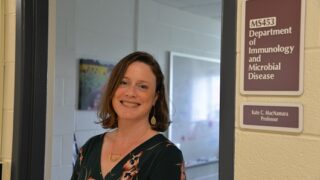 Researcher Kate MacNamara, PhD stands outside her office