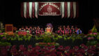 Albany Medical College graduates listen to a speaker at a podium on a stage at the 2025 Commencement ceremony