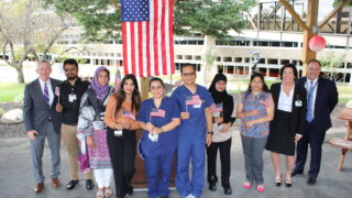 citizenship day ceremony a dozen employees in front of a flag