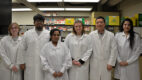 Six scientists in white coats standing together in Dr. Wei Sun's research lab