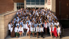 medical students in white coats sit on steps of Albany Medical College