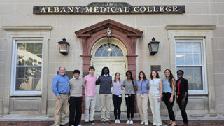 Group of students and professors standing together in front of Albany Medical College