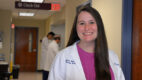 Plastic surgeon Dr. Christina Rudolph stands in a clinic hallway wearing a white coat
