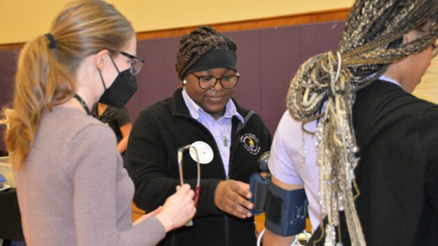 A female student at Albany Leadership Charter School takes part in a medical demonstration to take a patient's vital signs during a career event at the school.