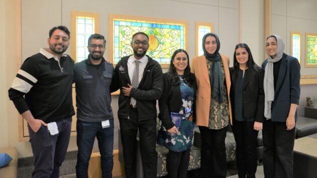 Students and providers stand together in the B Lobby at Albany Medical Center and post for a picture in a line at the Underrepresented Student Alliance End of the Year celebration.