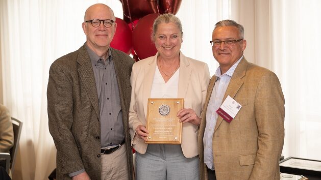 Three doctors standing together, holding an award