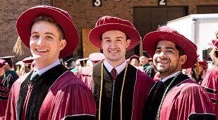 Three men in caps and gowns at graduation