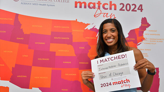 An Internal Medicine-Pediatrics resident stands in front of the 2024 Match Day map.