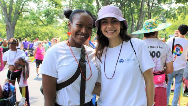 Participants in the 2023 Capital Pride Parade smile and pose for a photo while wearing Albany Med Health System T-shirts.