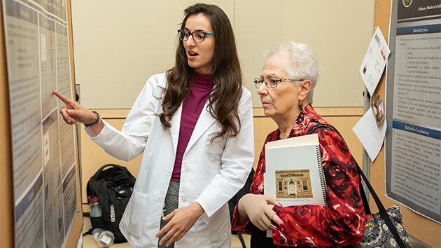 A student discusses a project with a spectator.