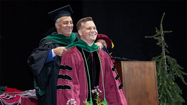 A student and an administrator on stage at the College Commenecement.