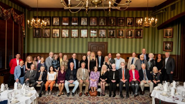 A large group of people gathering for a class photo at their class reunion.