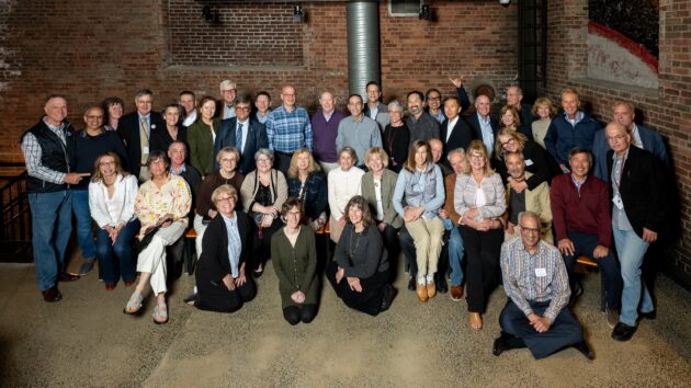 A large group of people gathering for a class photo at their class reunion.