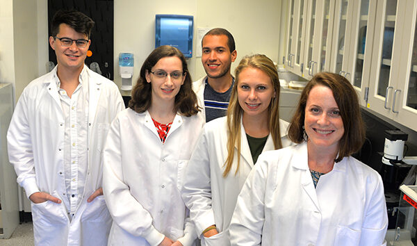 Graduate students in biomedical science pose with their instructor in their lab