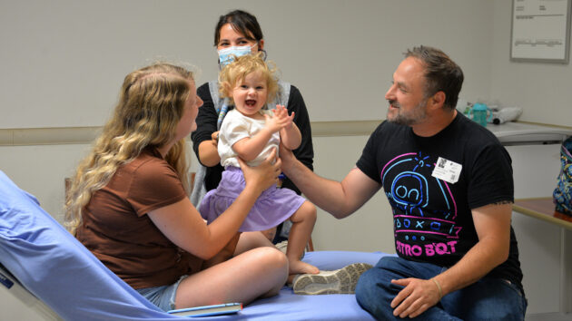 A joyous pediatric patient with her parents and doctor