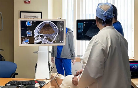 Neurosurgery residents in a classroom training session  viewing brain scans displayed on a monitor