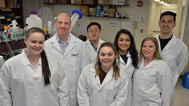 Graduate students in biomedical sciences pose for a photo in their lab