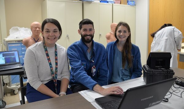 Three pediatric residents working at a computer, smiling